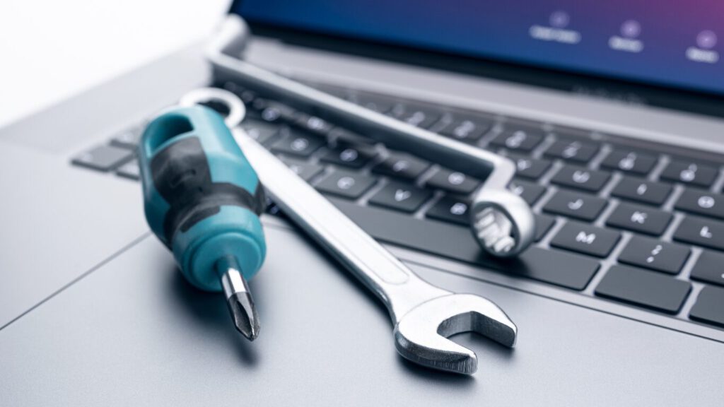 Schroevendraaier en steeksleutel op een laptop als symbool voor technisch website onderhoud en ondersteuning.